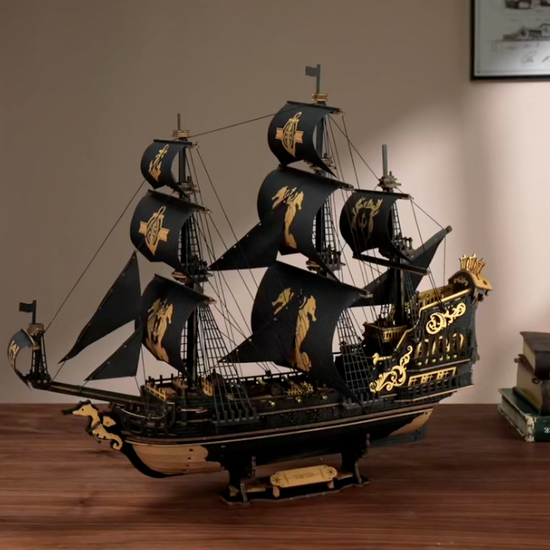 Puzzle 3D : Galion Noir et Or en Bois, modèle assemblé sur un bureau en noyer, voiles noires